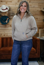 Load image into Gallery viewer, A woman wearing a light beige quarter-zip fleece pullover and blue jeans, standing in front of a rustic wood-paneled wall with a brown velvet sofa and hats in the background.
