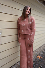Load image into Gallery viewer, A woman wearing a matching dusty rose knit lounge set with white horseshoe patterns, standing against a beige house siding wall.
